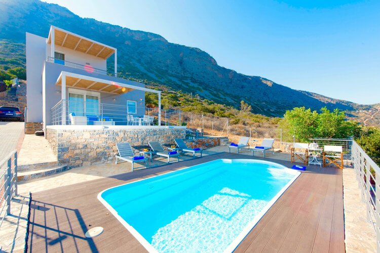A modern villa with mountain backdrop and pool in the foreground