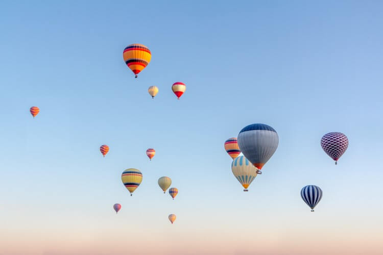 Multiple hot air balloons in the sunrise sky.