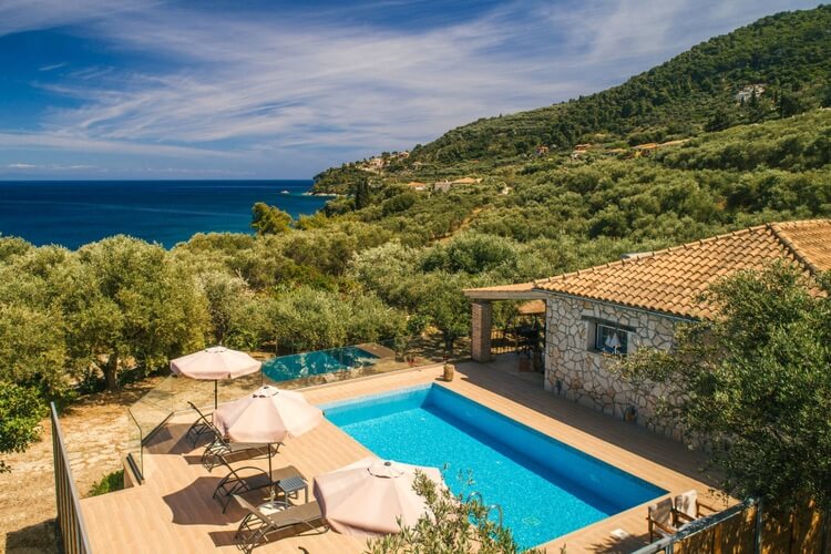 Pool, sun lounger, stone villa with sea background