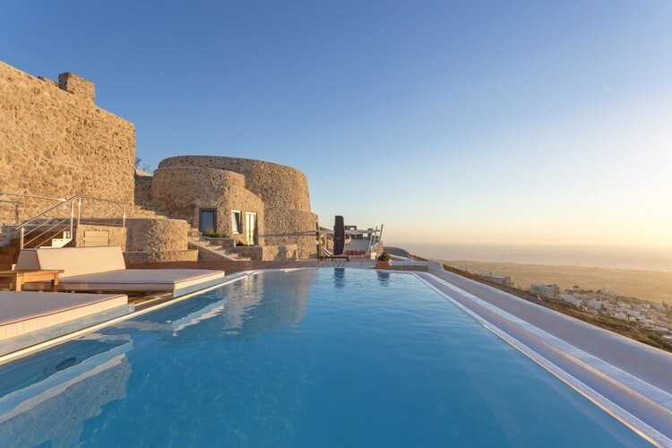 Large infinity pool with sunset sea view on the right, yellow stone villa on the right