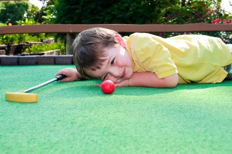 A young child aiming for the next shot. 