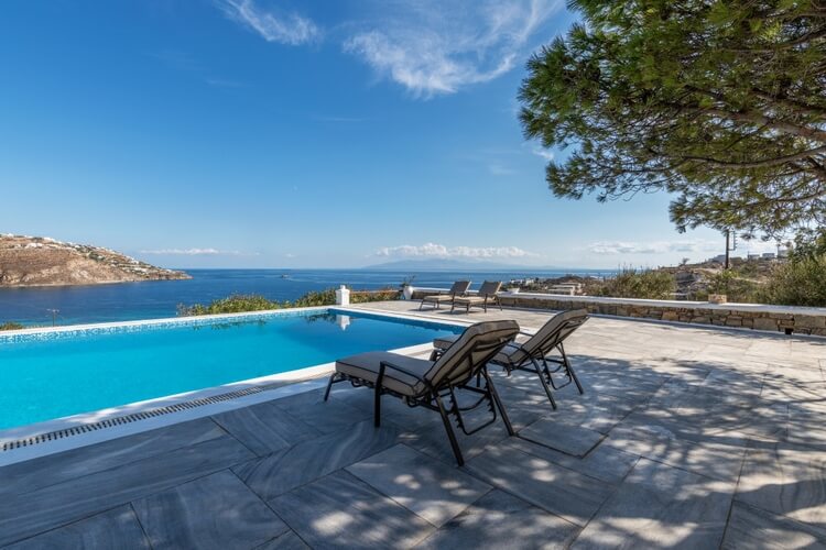 Two sun loungers in front of the infinity pool overlooking the ocean and distant islands