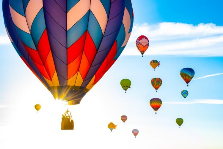 Multiple hot air balloons in the sun.