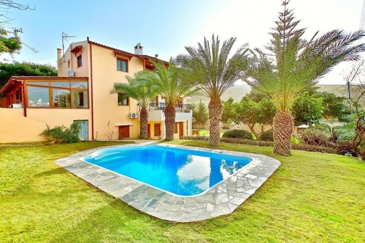 Orange villa with palm trees and pool in lush garden