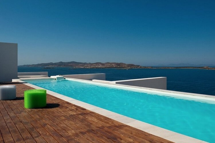 Wood deck and large infinity pool overlooking the sea and land in the distance